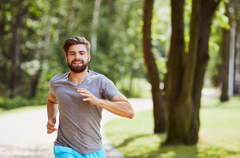 Junger Mann joggt durch einen Park